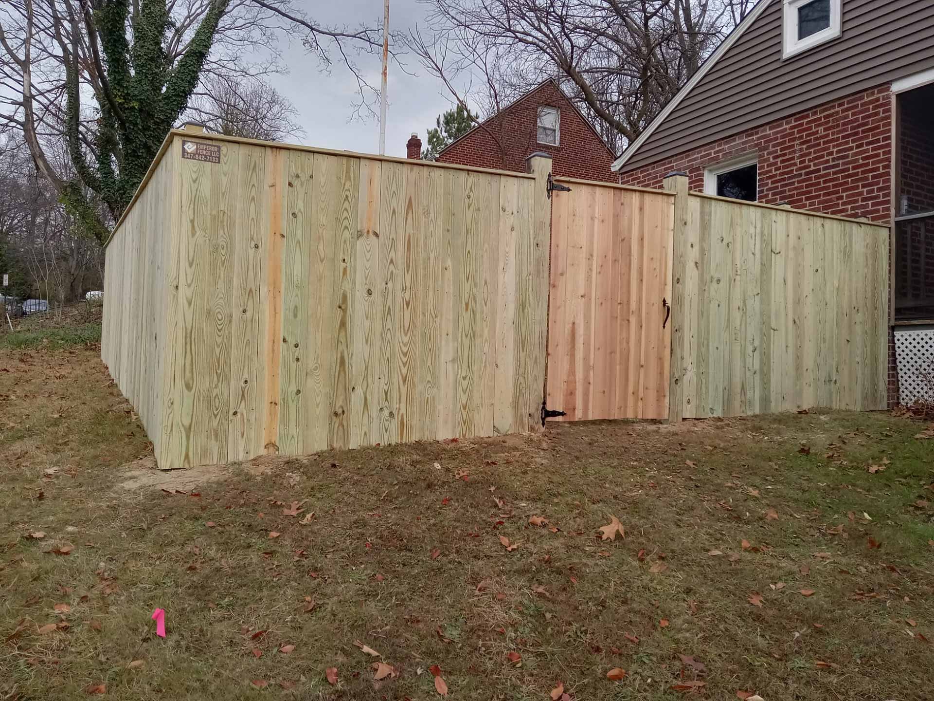Wooden privacy fence with man door installed by Emperor Fence LLC
