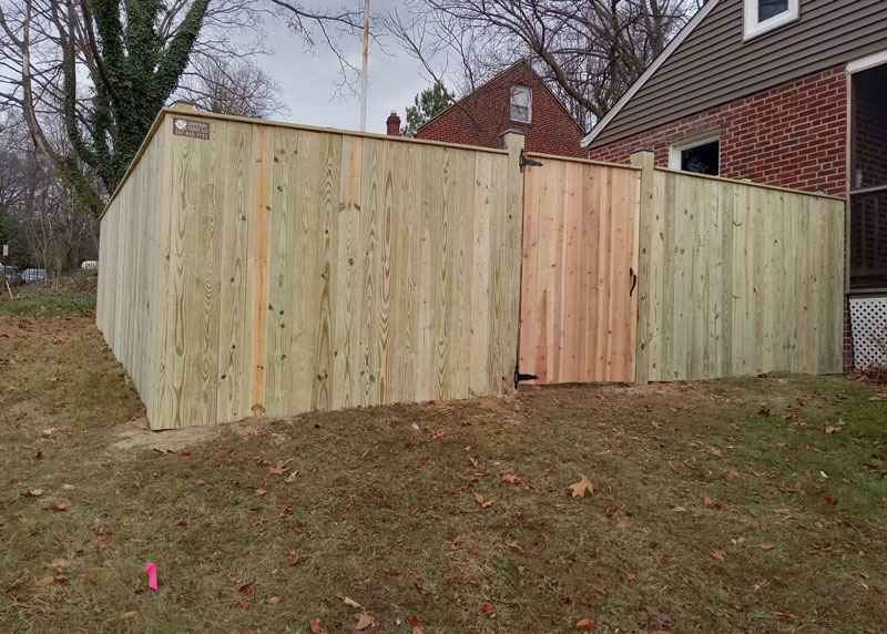 Wooden privacy fence with man door installed by Emperor Fence LLC