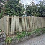 Wooden property fence on top of stone retaining wall