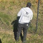 worker in Emperor Fence LLC uniform installing a chain link fence